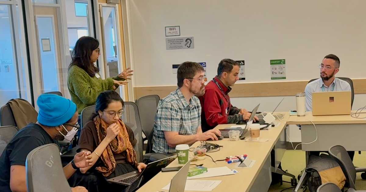 Hackathon attendees working on their apps while Rajshree assists.